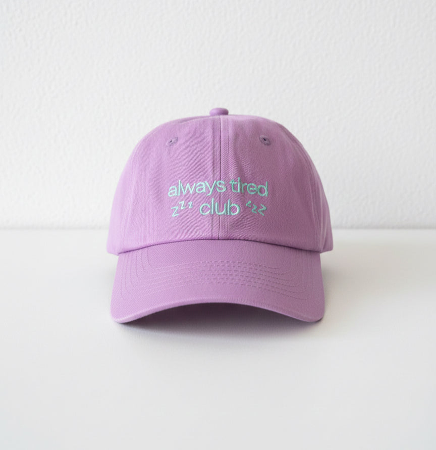 Purple cap with 'always tired zzz' text on a white background