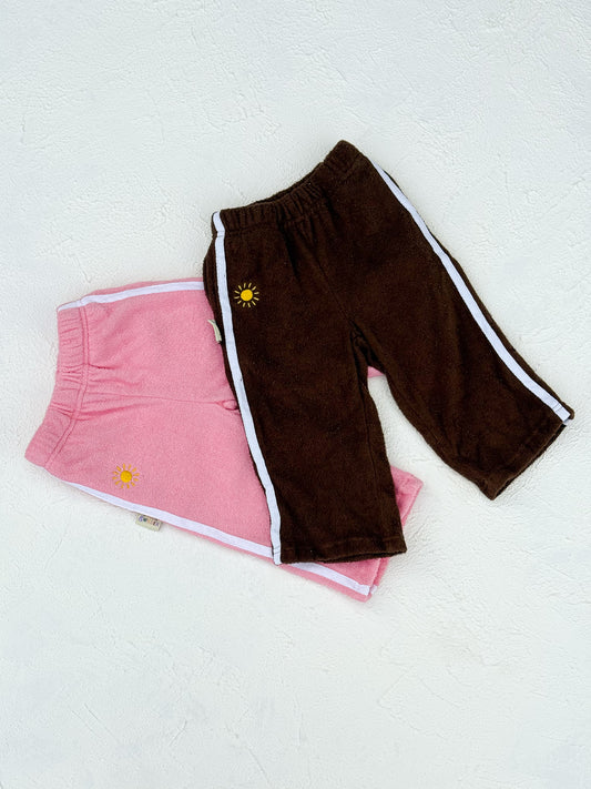 Pink shorts and brown pants with a sun design on a white background