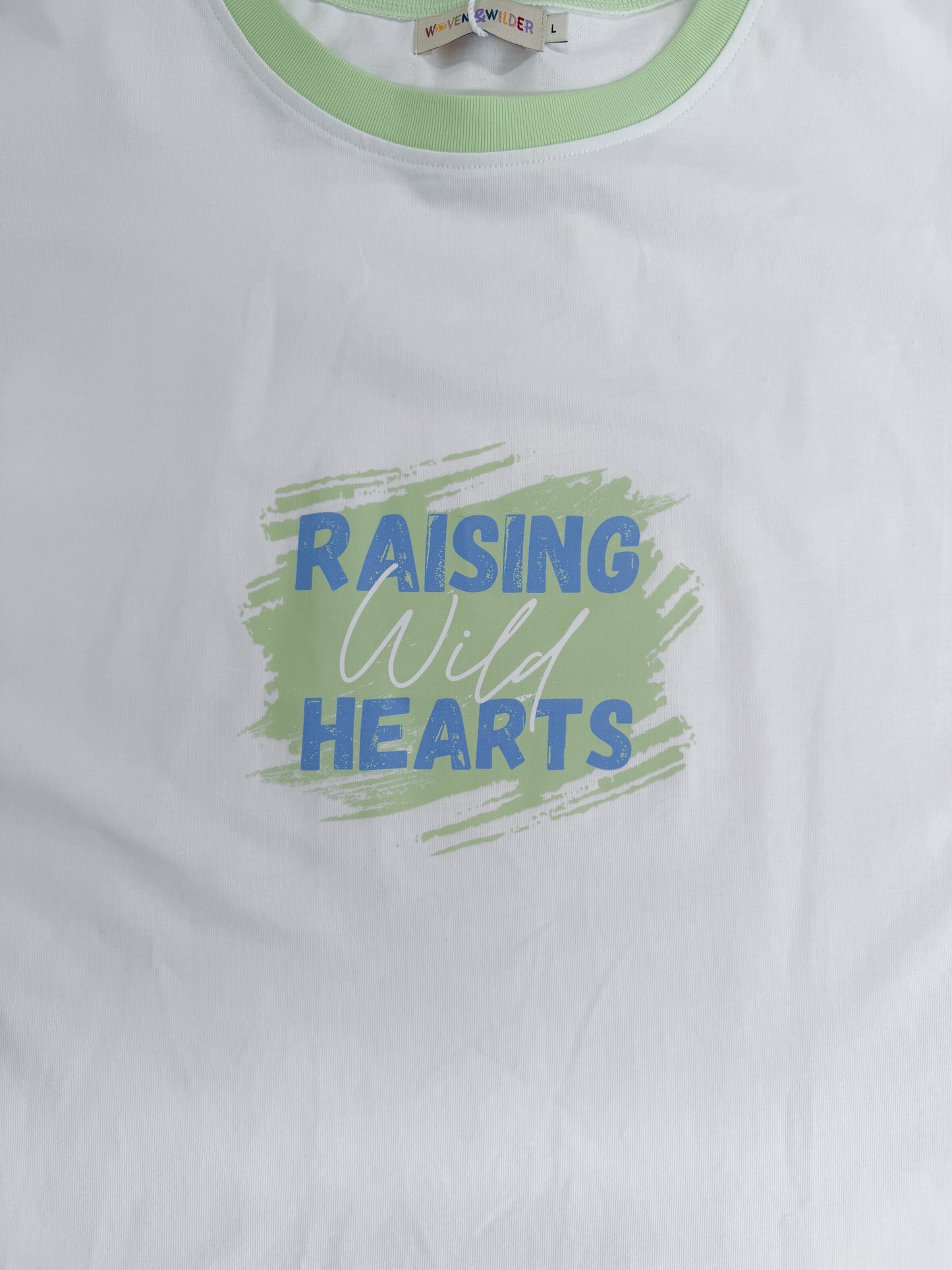 White t-shirt with 'Raising Wild Hearts' text and green border on a white background