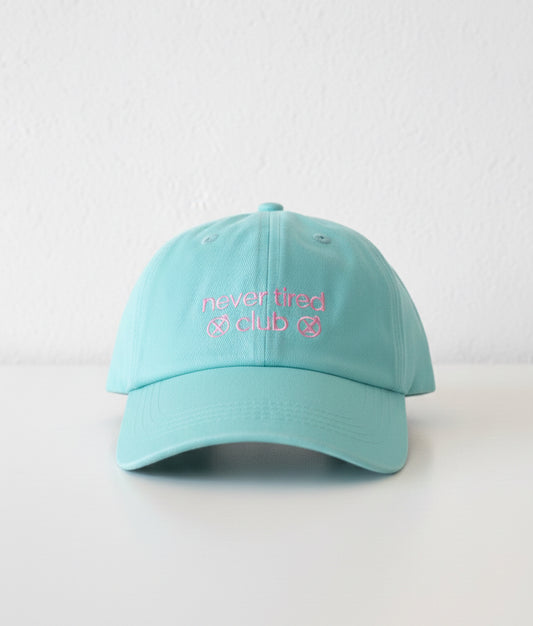 Light blue cap with 'never tired club' text on a white background