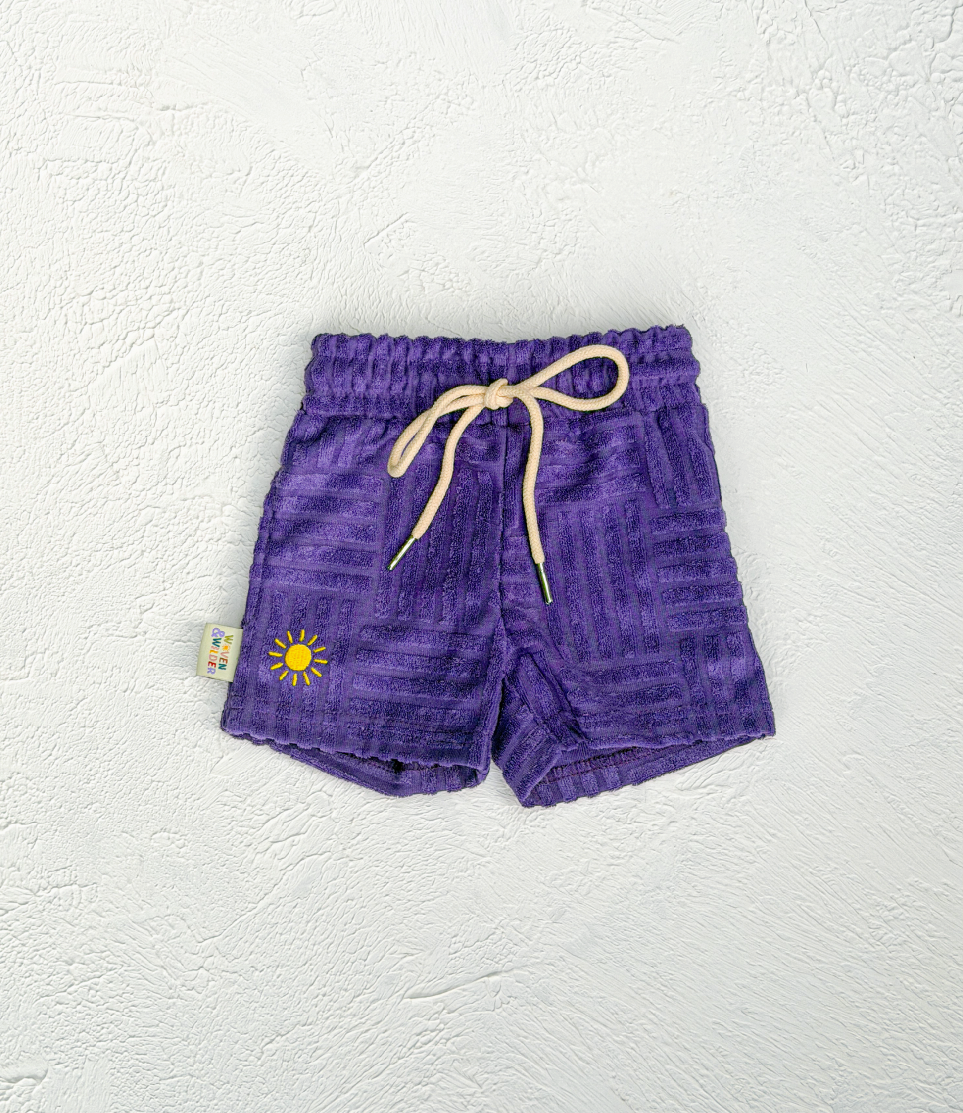 Purple shorts with a yellow sun design on a white background