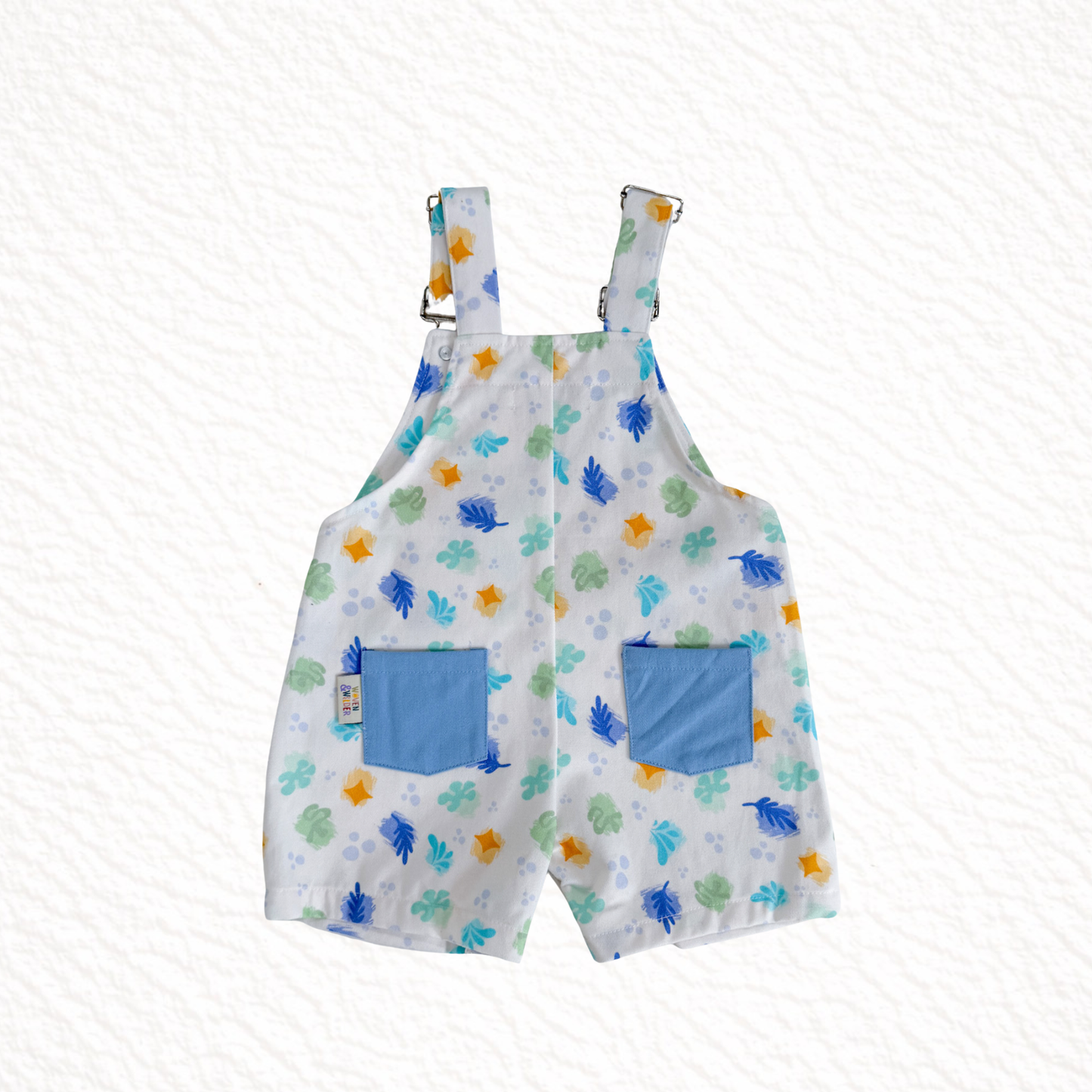 Children's overalls with a floral pattern and blue pockets on a white background