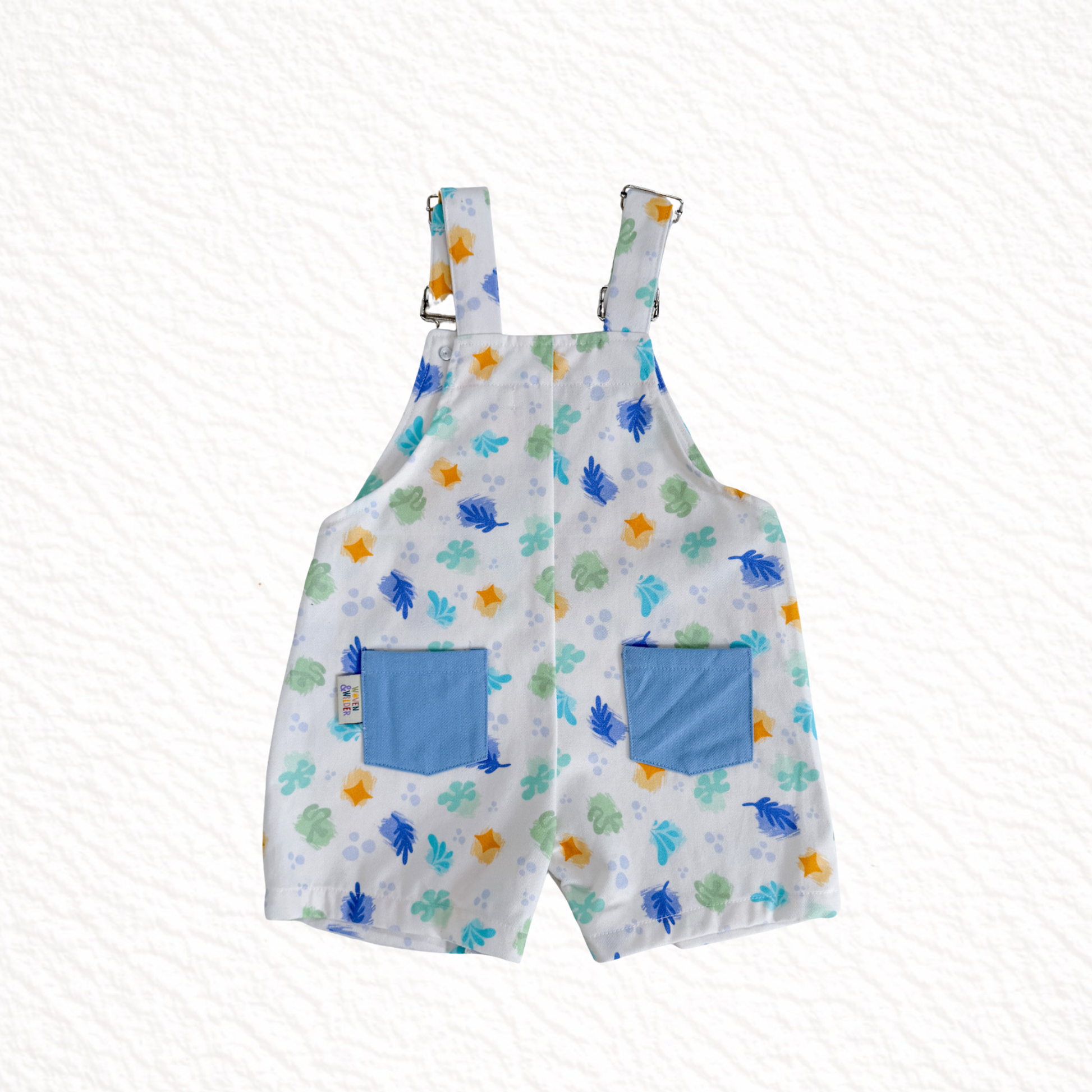 Children's overalls with a floral pattern and blue pockets on a white background