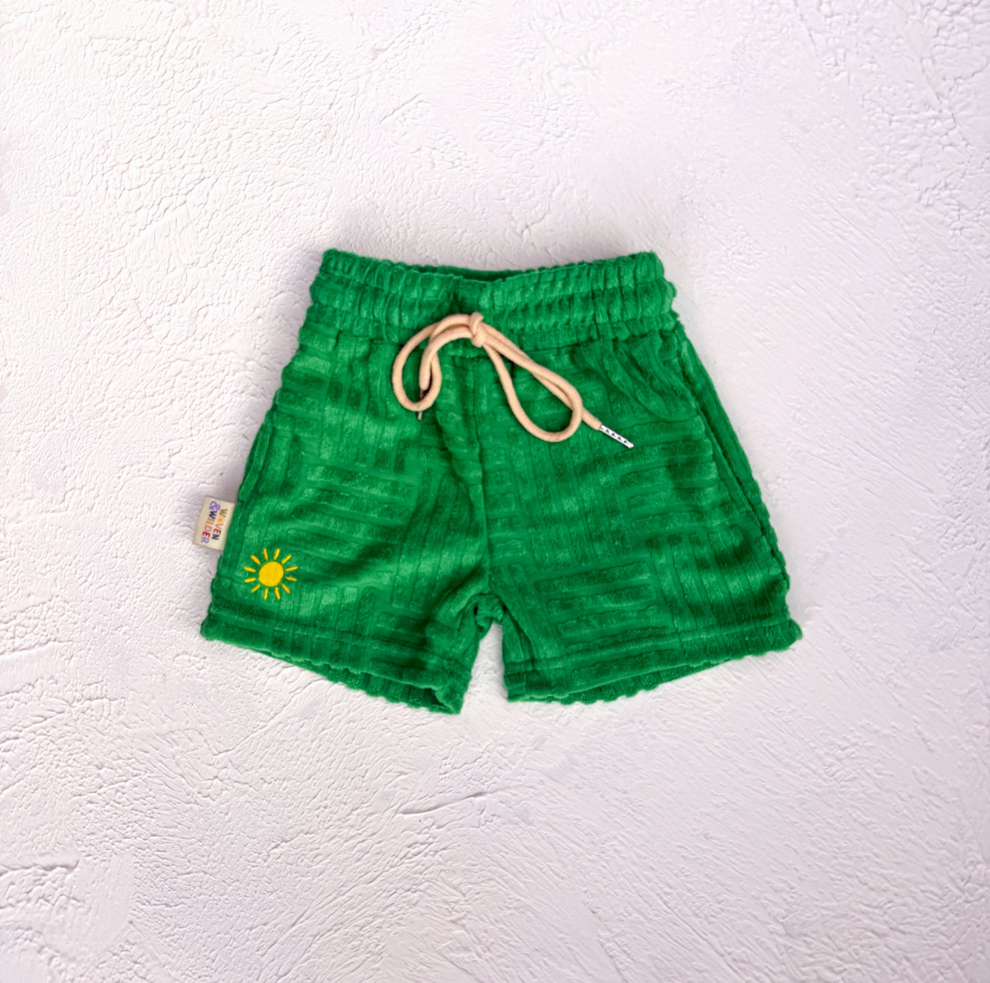 Green shorts with a sun design on a white background