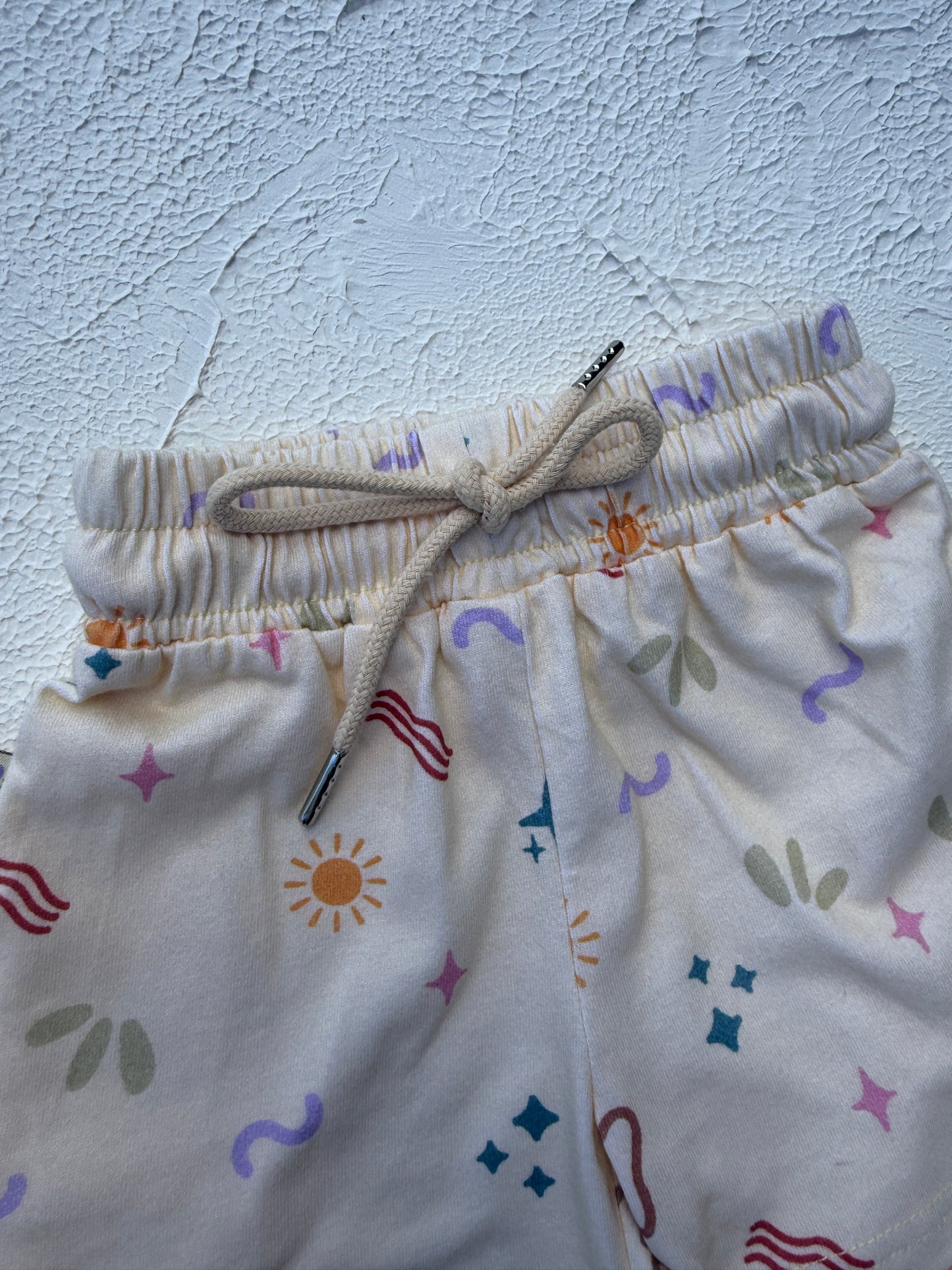 Baby romper with colorful patterns on a textured white background