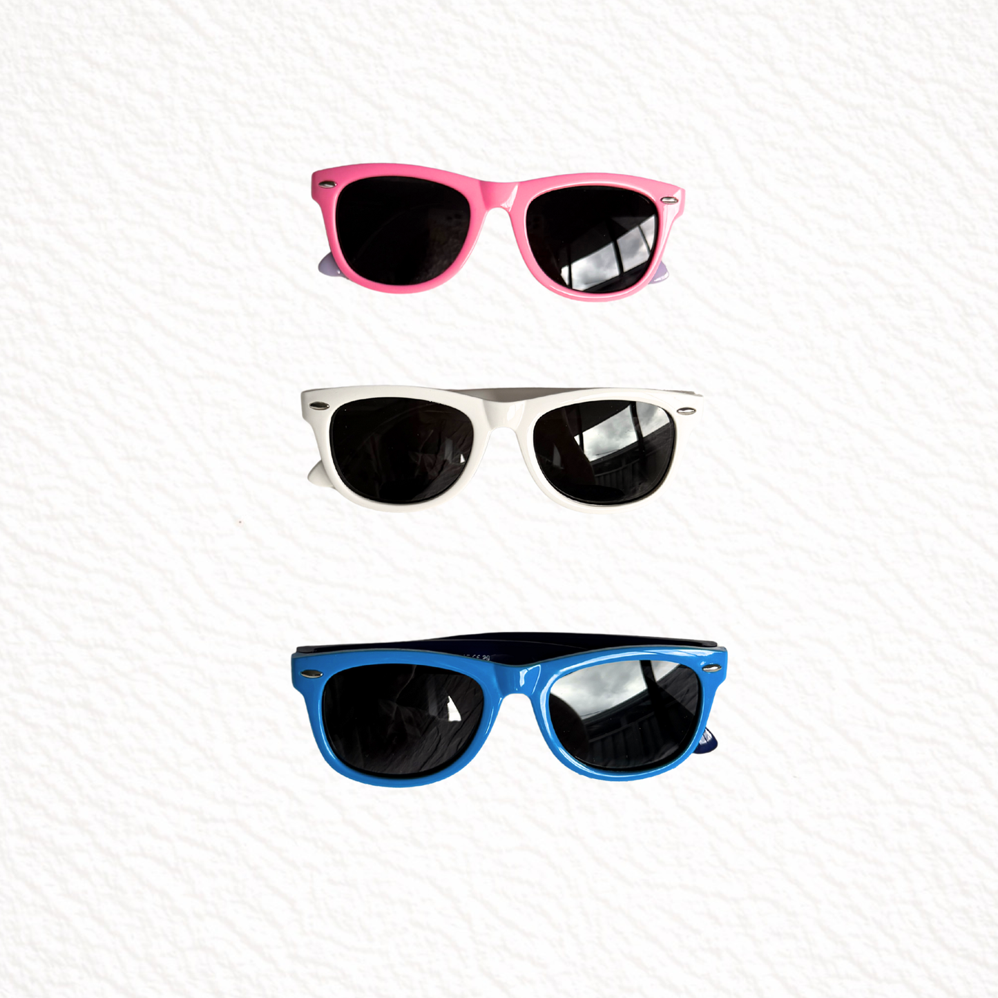 Three pairs of sunglasses with pink, white, and blue frames on a white background