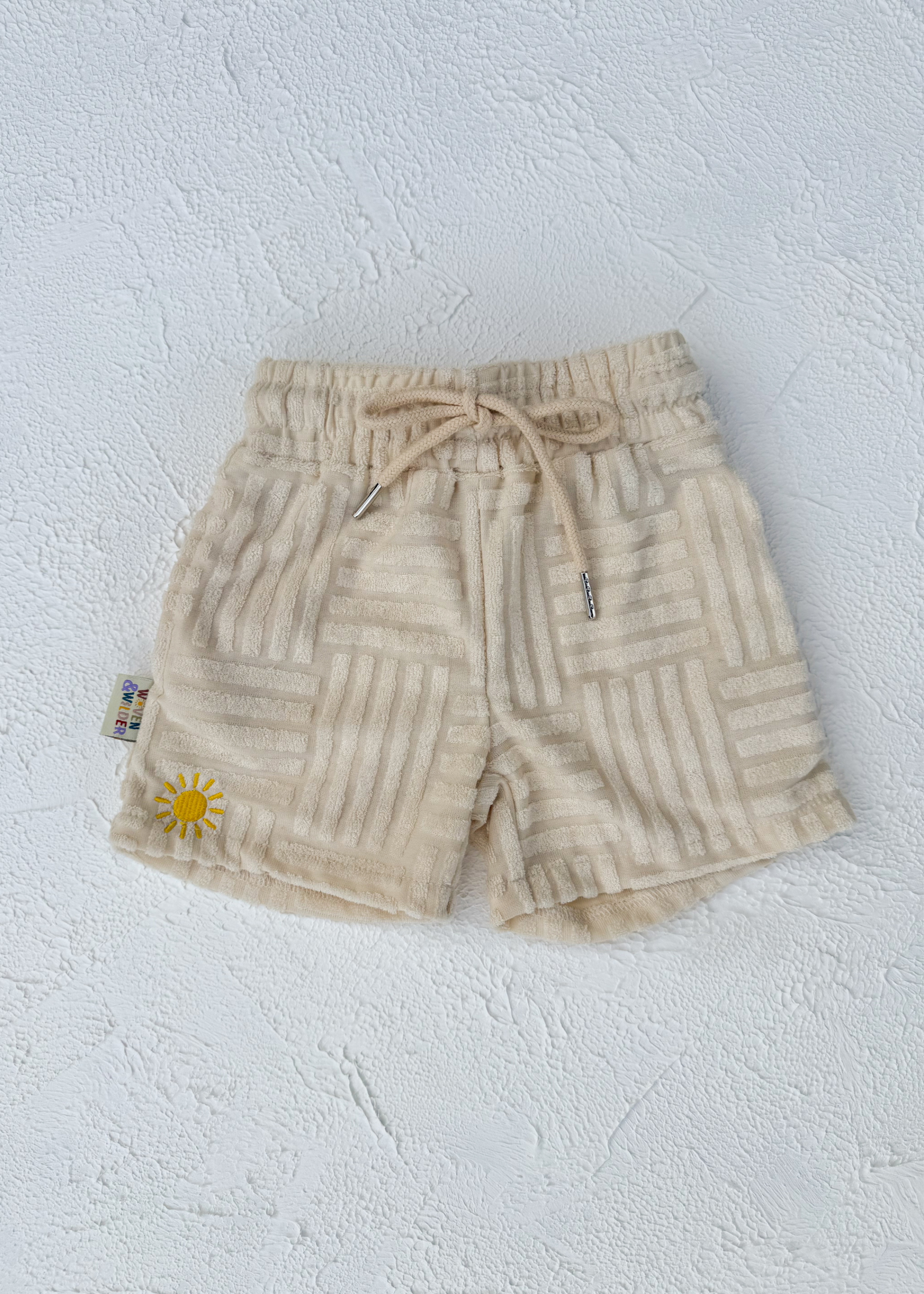 Beige shorts with a sun design on a light gray background