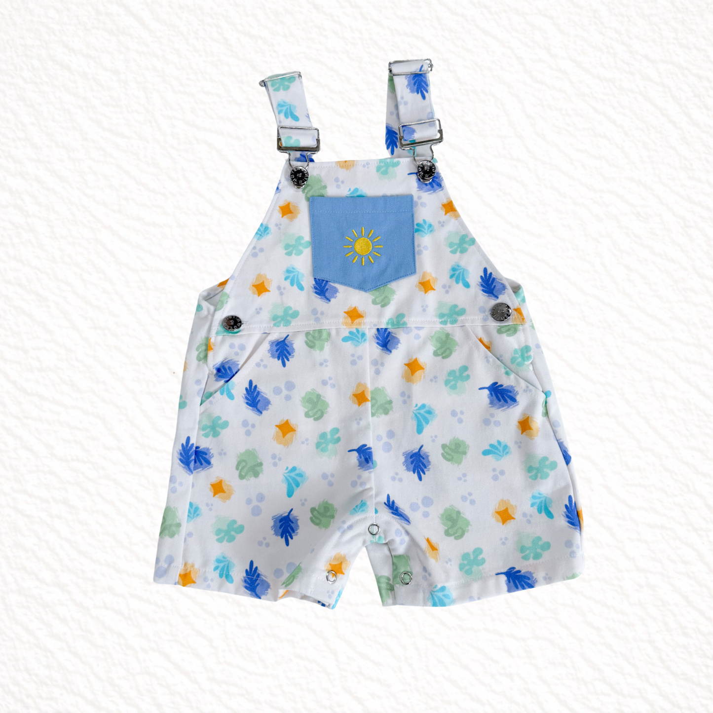 Children's overalls with colorful animal print and blue pocket on a white background