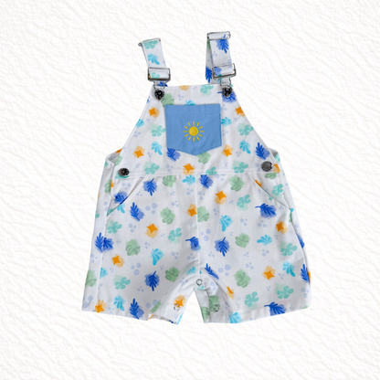 Children's overalls with colorful animal print and blue pocket on a white background