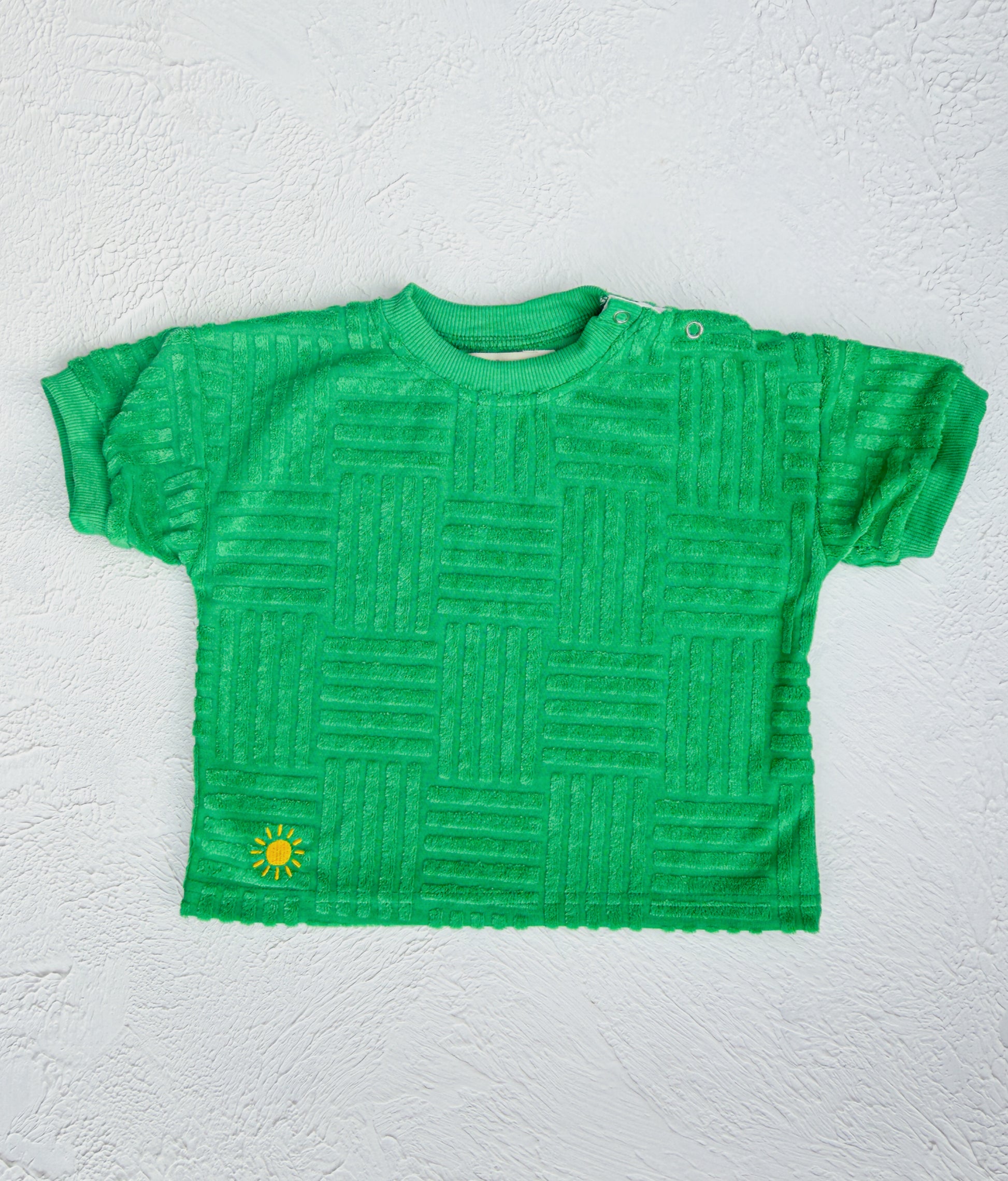 Green textured t-shirt with a small yellow logo on a white background