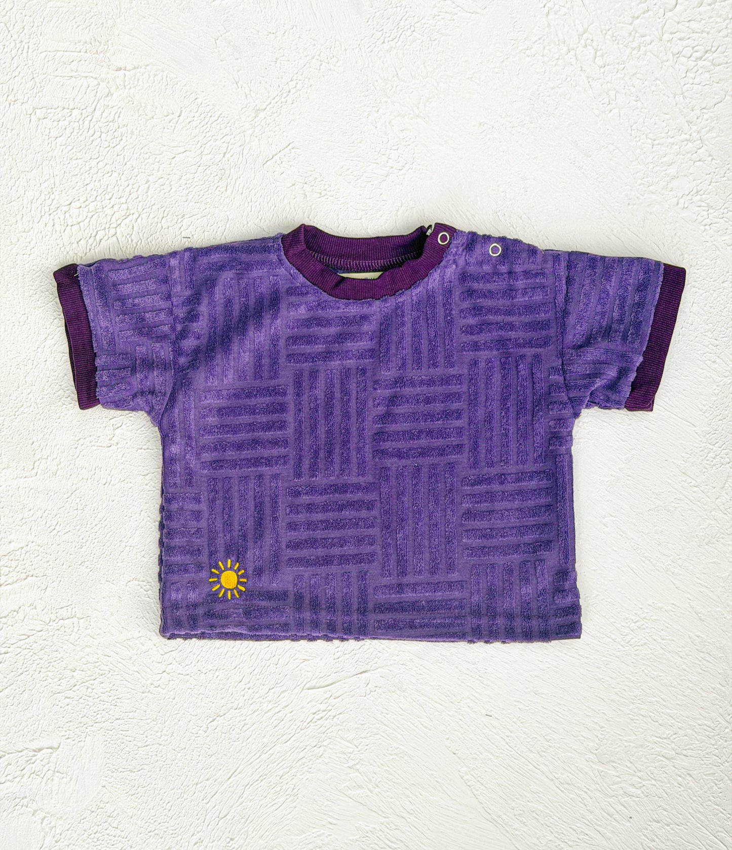 Purple textured t-shirt with a yellow sun design on a white background