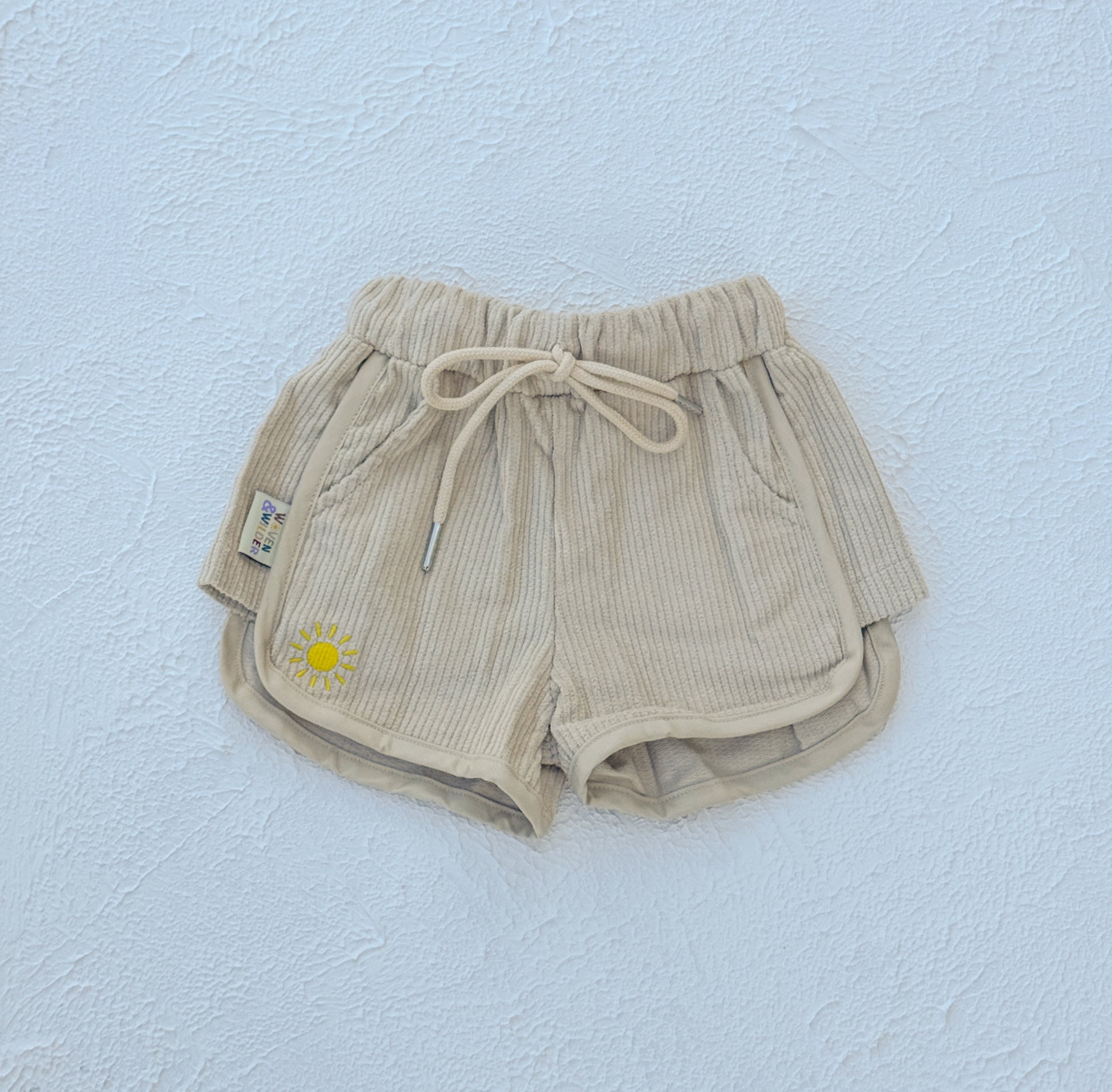 Beige shorts with a sun design on a light blue background