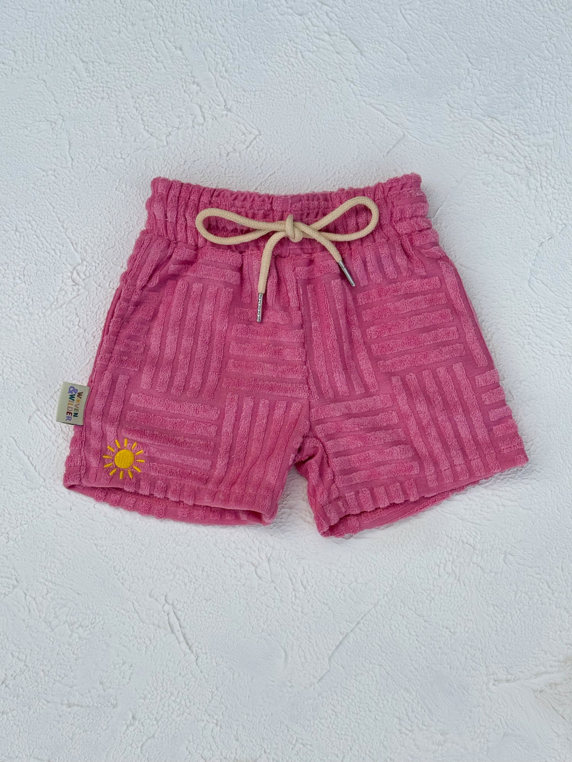 Pink shorts with a sun design on a white background