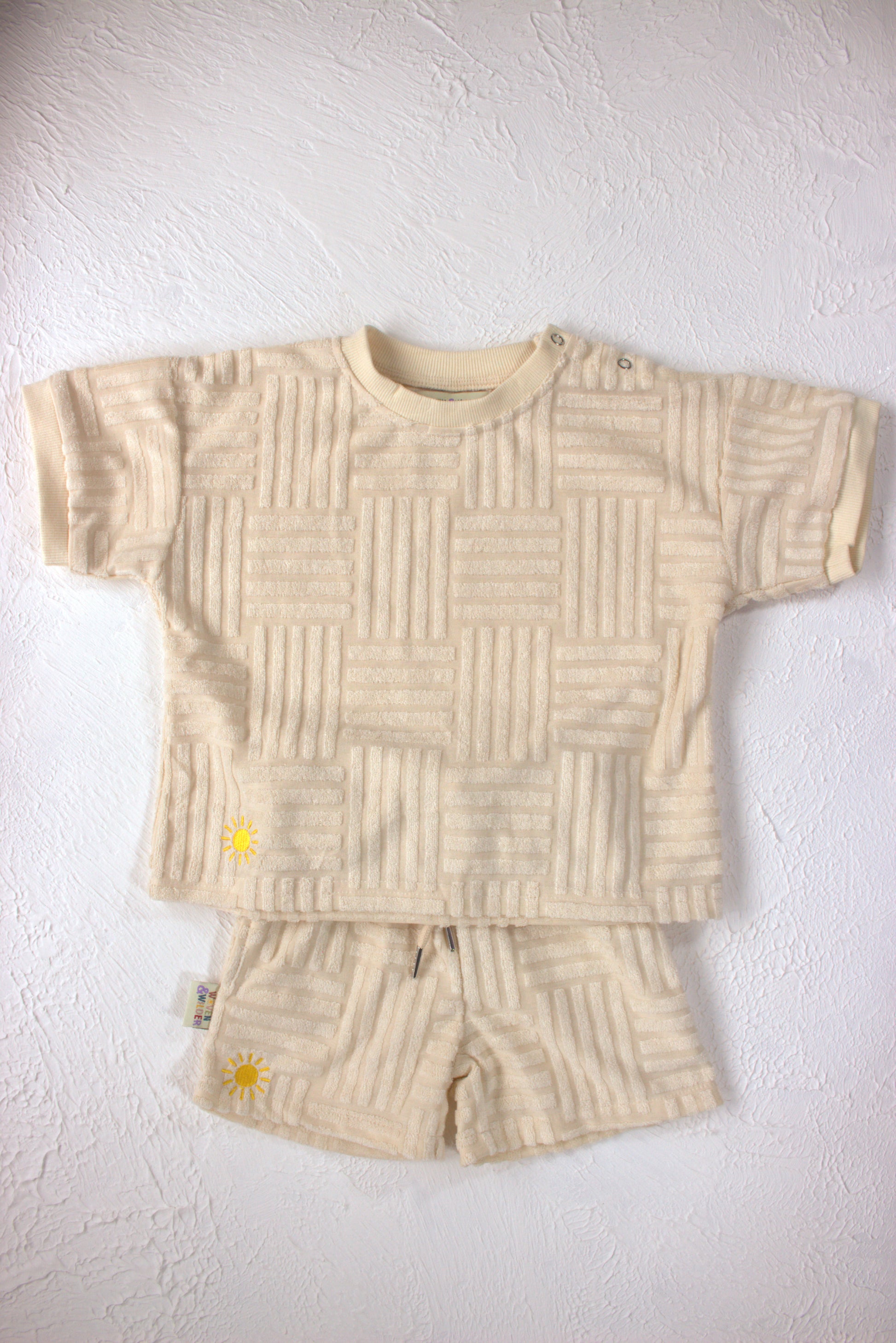 Beige textured shirt and shorts set on a white background