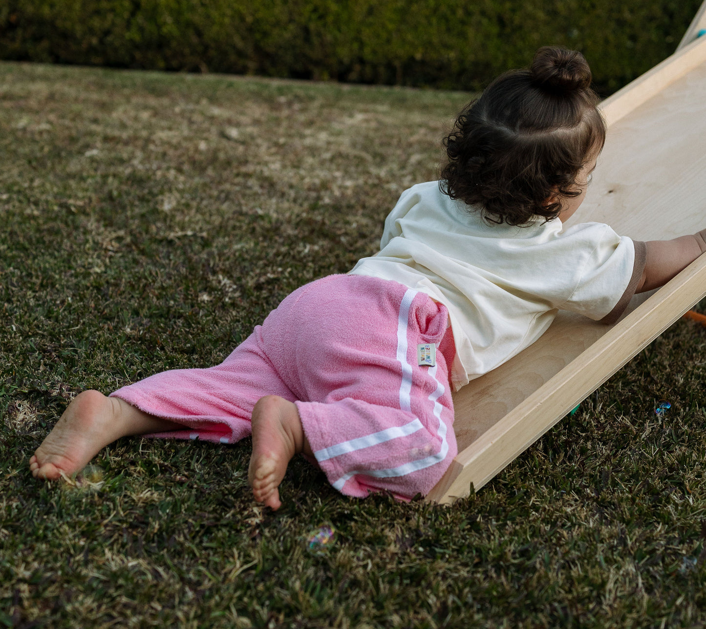 Child sliding down a small wooden slide on grass