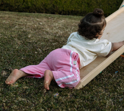 Child sliding down a small wooden slide on grass