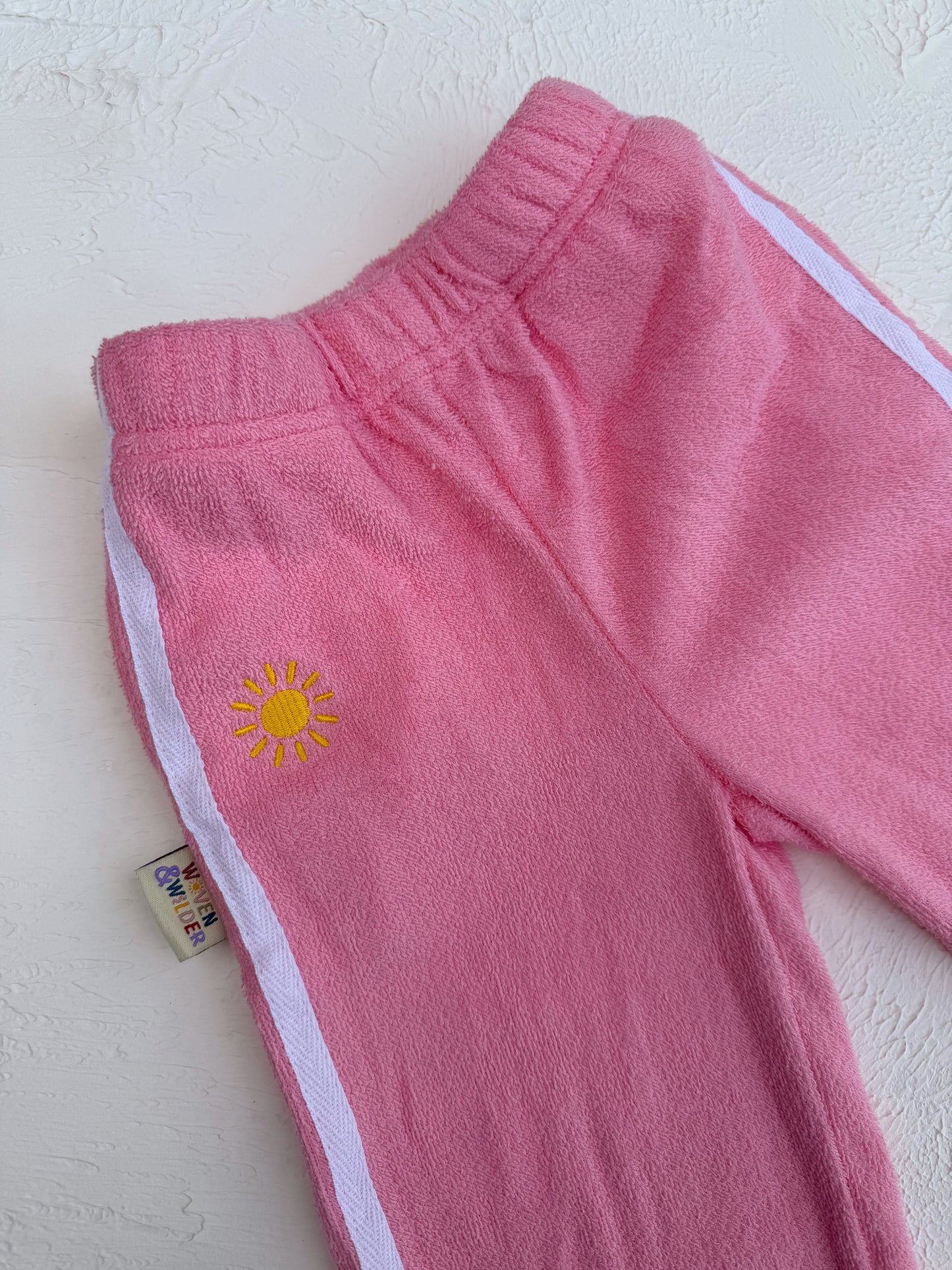 Pink pants with a yellow sun design on a white background