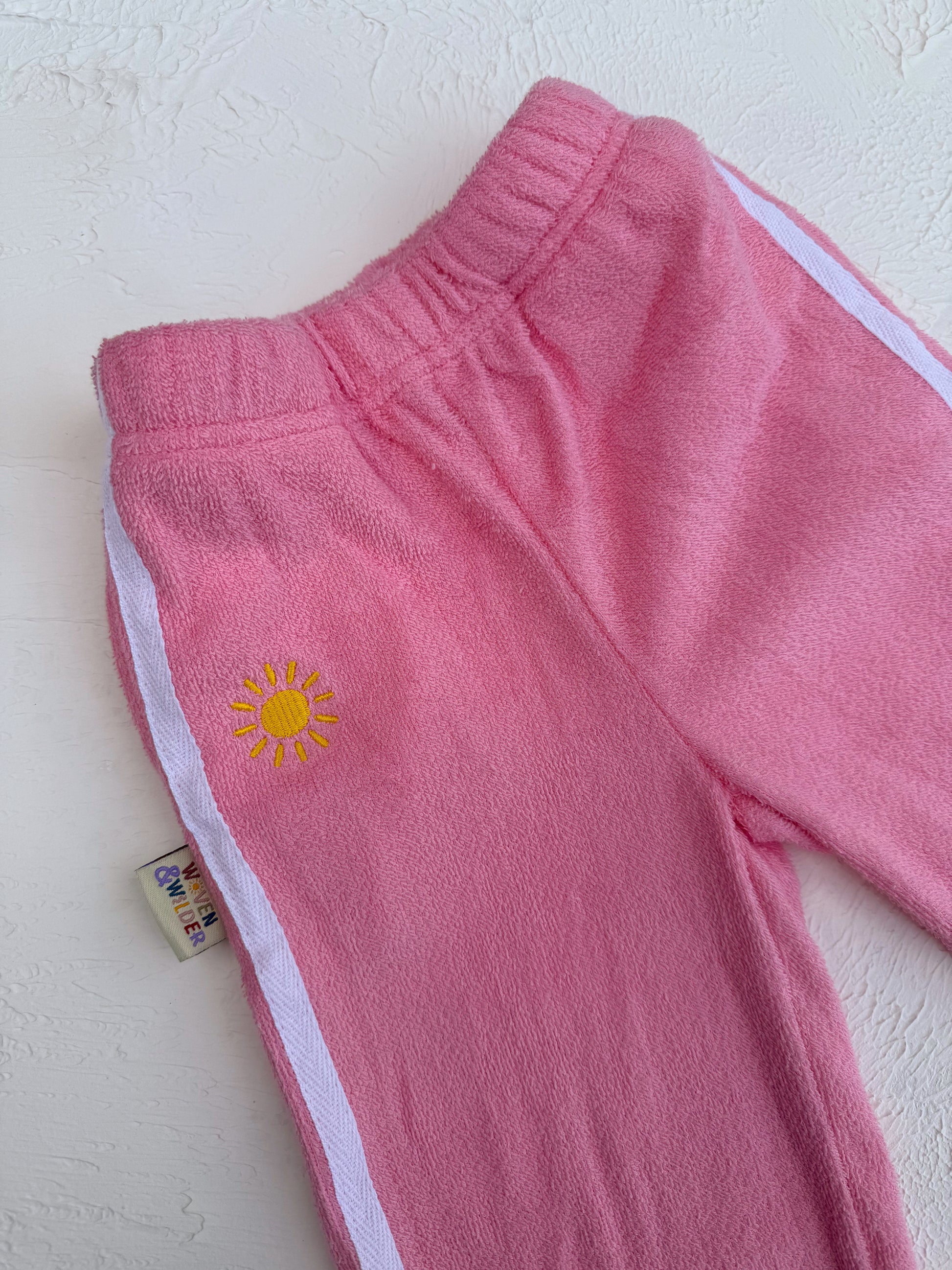 Pink pants with a yellow sun design on a white background