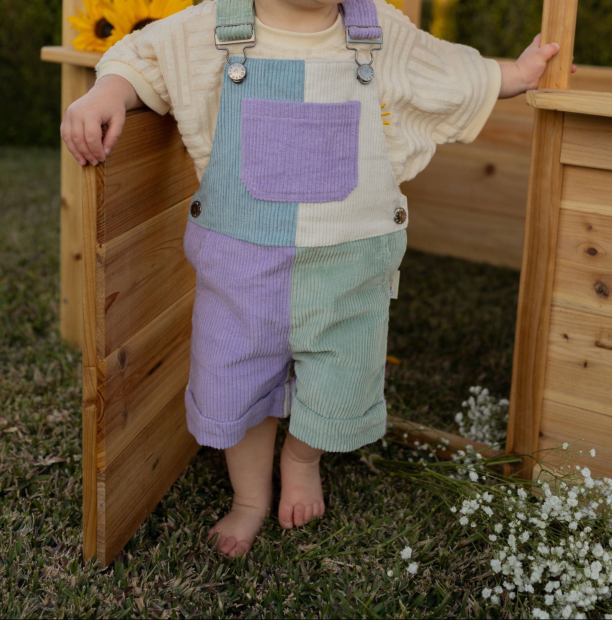 Child standing in a wooden playhouse with a blurred natural background