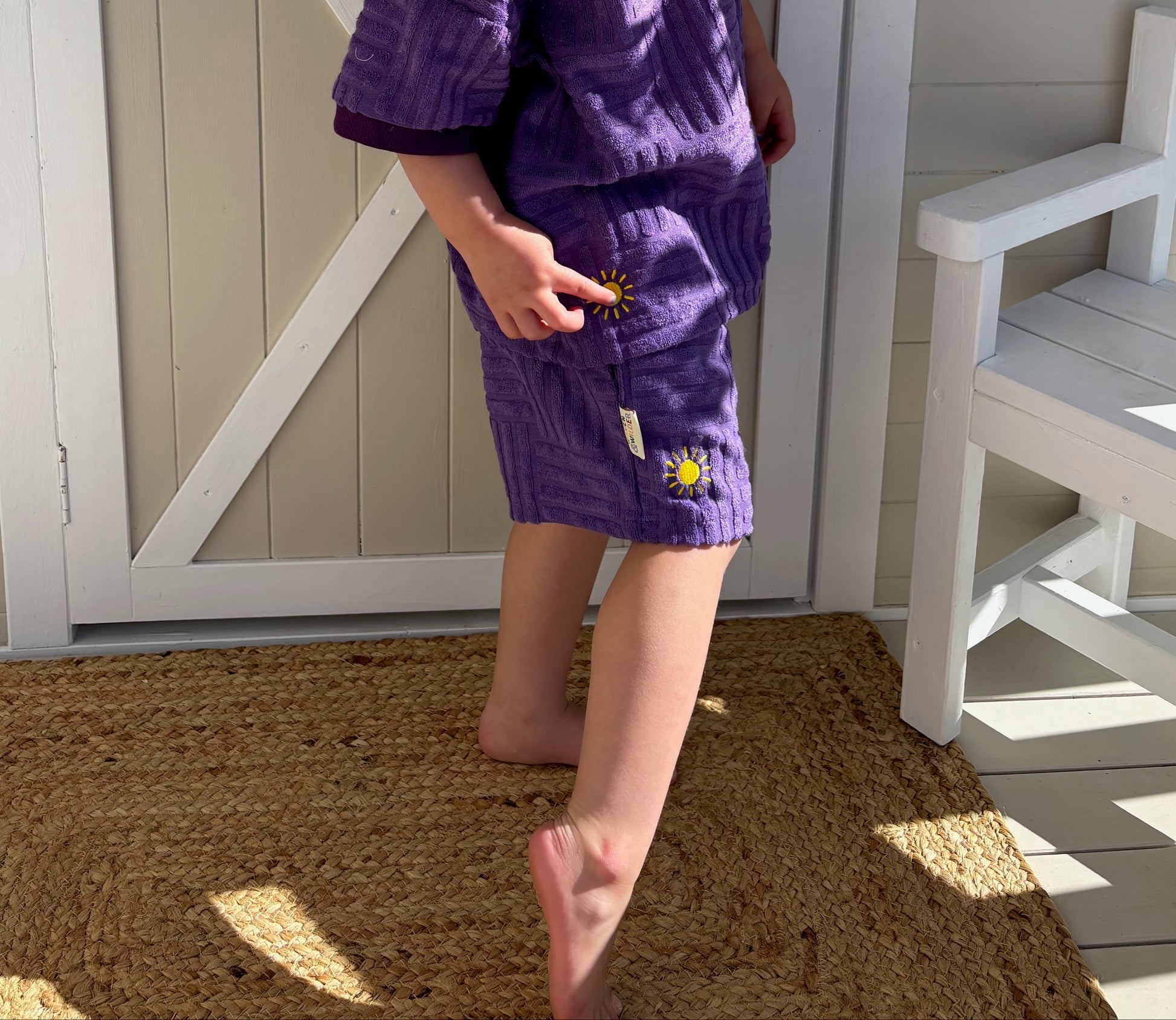 Child in a purple outfit standing in front of a wooden shed with 'Oaklee's Cubby' sign.